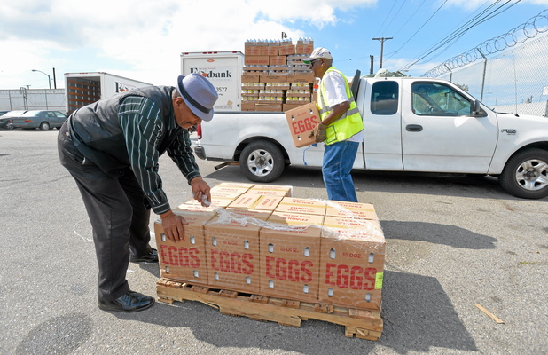 Bishop Gene Townsley, left, and Percy Polk from Heavenly Hope load eggs, canned good and other food into two trucks at the Food Bank in Long Beach, CA on Thursday, July 17, 2014. The Food Bank of Southern California typically gets three containers of food delivered each day to provide to area agencies who make weekly pickups.  (Photo by Scott Varley, Daily Breeze)